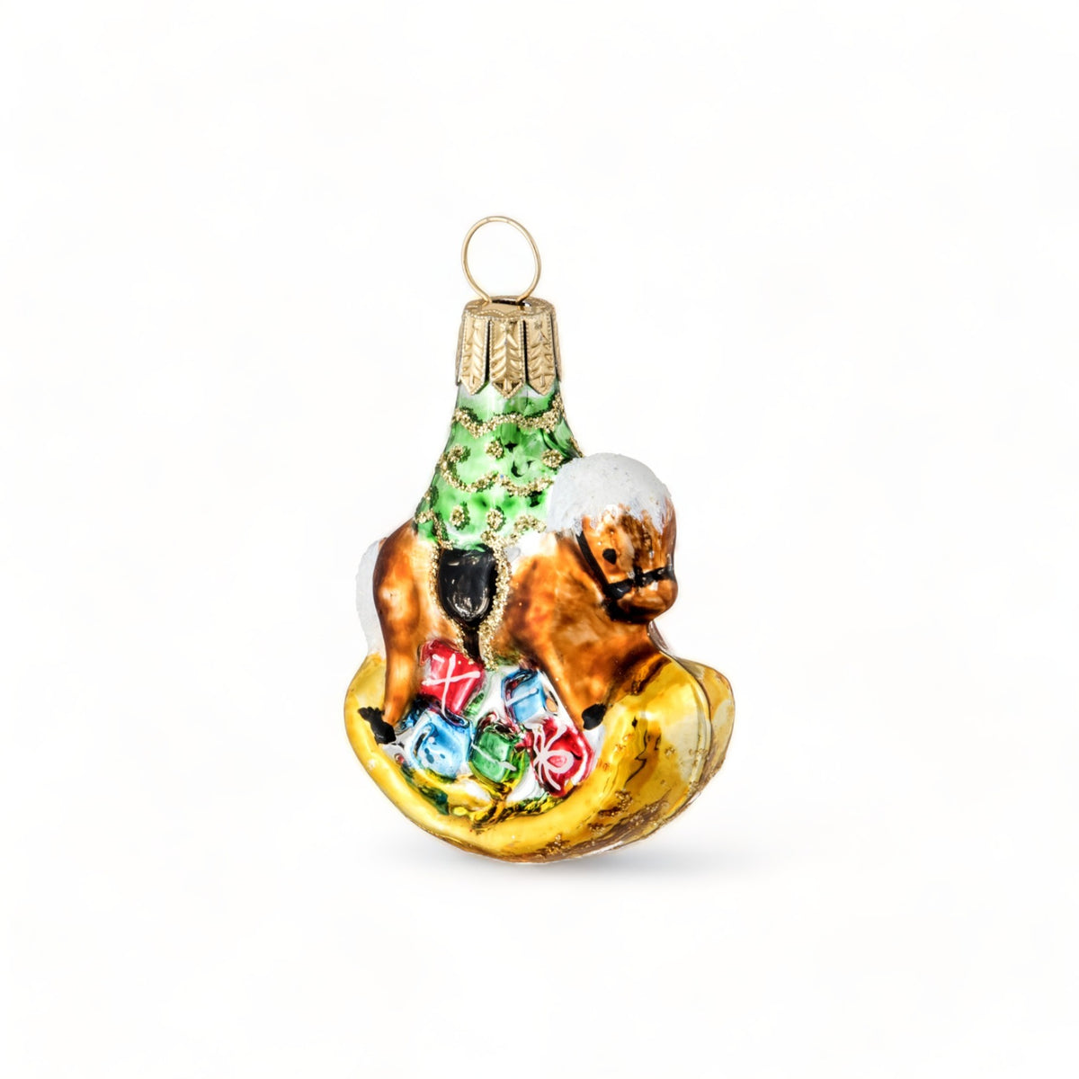 Suspension en verre soufflé, chromée et peinte à la main en forme de cheval à bascule avec une crinière blanche et une selle noire. Il a des paquets cadeaux entre les pattes et un sapin décoré d'une guirlande dorée sur le dos. 