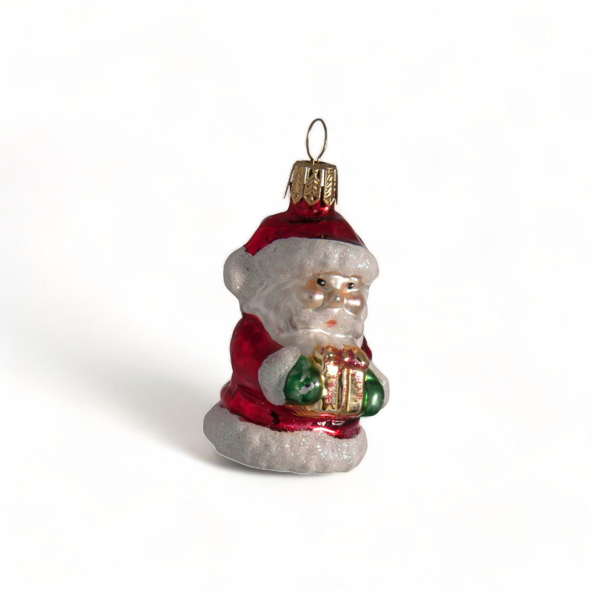 Suspension en verre soufflé, chromée et peinte à la main en forme de père Noël vêtu de son habit rouge, de gants verts et portant un cadeau doré serti d'un nœud rouge. La fourrure de son habit et de son bonnet est représenté en paillettes blanches.