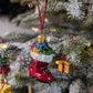 Suspension en verre soufflé, chromée et peinte à la main en forme de botte du Père Noël remplie de paquets cadeaux colorés vert, bleu, rose et doré. La fourrure de la botte est représentée par des paillettes blanches.