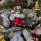 Suspension en verre soufflé, chromée et peinte à la main en forme de botte du Père Noël remplie de paquets cadeaux colorés vert, bleu, rose et doré. La fourrure de la botte est représentée par des paillettes blanches.