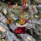 Suspension en verre soufflé, chromée et peinte à la main en forme de botte du Père Noël remplie de paquets cadeaux colorés vert, bleu, rose et doré. La fourrure de la botte est représentée par des paillettes blanches.