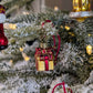 Suspension de Noël en verre soufflé, chromée et peinte à la main en forme de paquet cadeau doré avec un ruban rouge aux liserés dorés pailletés qui se termine par un nœud sur le dessus du cadeau. Suspension de Noël en verre soufflé, chromée et peinte à la main en forme de cloche dorée et paillettes argentées.