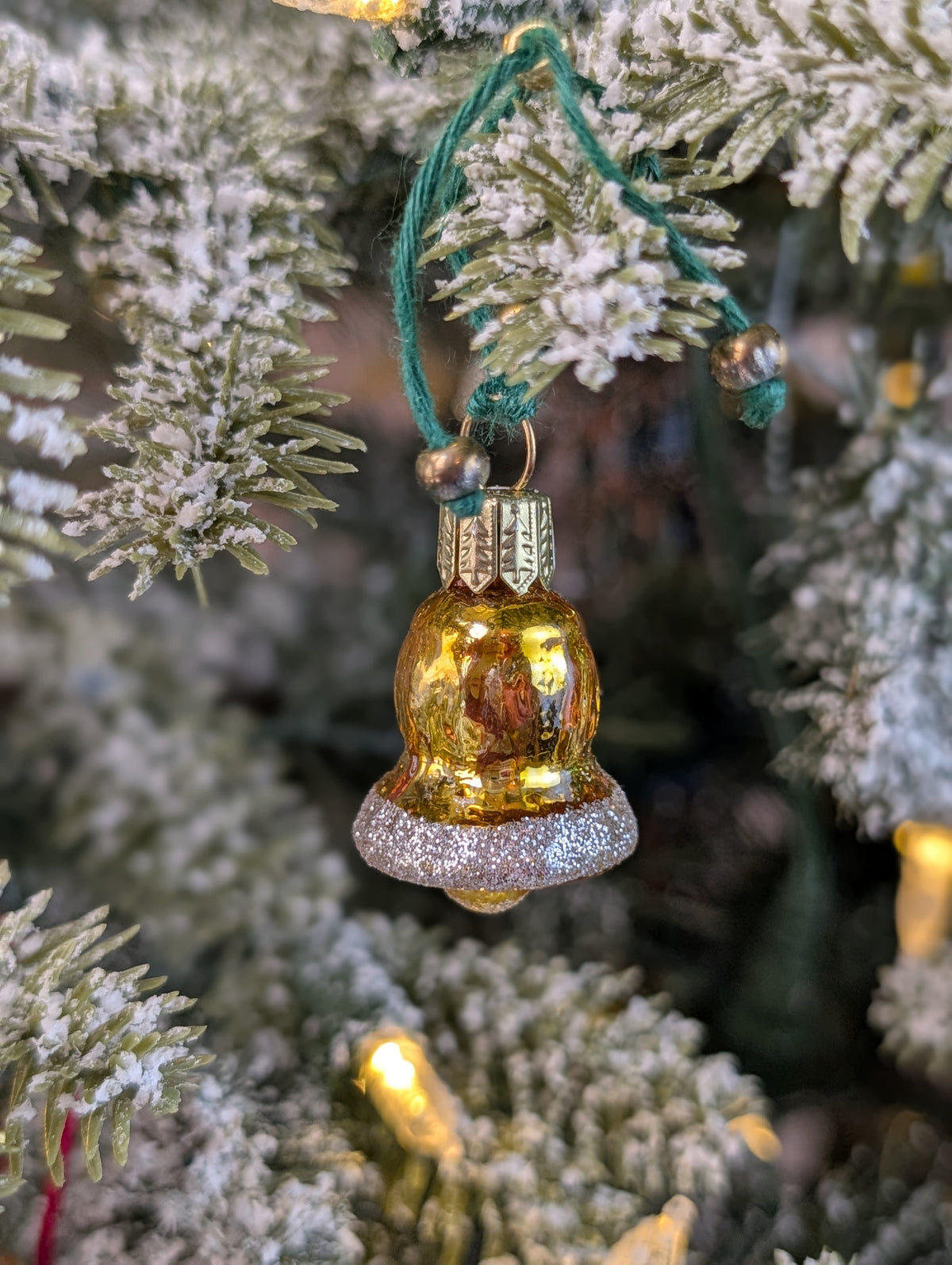 Suspension en verre soufflé, chromée, peinte et pailletée à la main en forme de cloche dorée, le bord est orné de paillettes argentées.