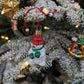 Vu de hauteur de la suspension de Noël en verre soufflé puis pailleté en forme de bonhomme de neige avec un bonnet et nez rouges et une écharpe et des gants verts. 