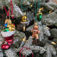 Suspensions de Noël en verre soufflé, chromées et peintes à la main en forme de bonhomme en pain d'épices, de botte du père Noël remplie de cadeaux, de cloche dorée avec paillettes argentées et de couronne de noël verte.