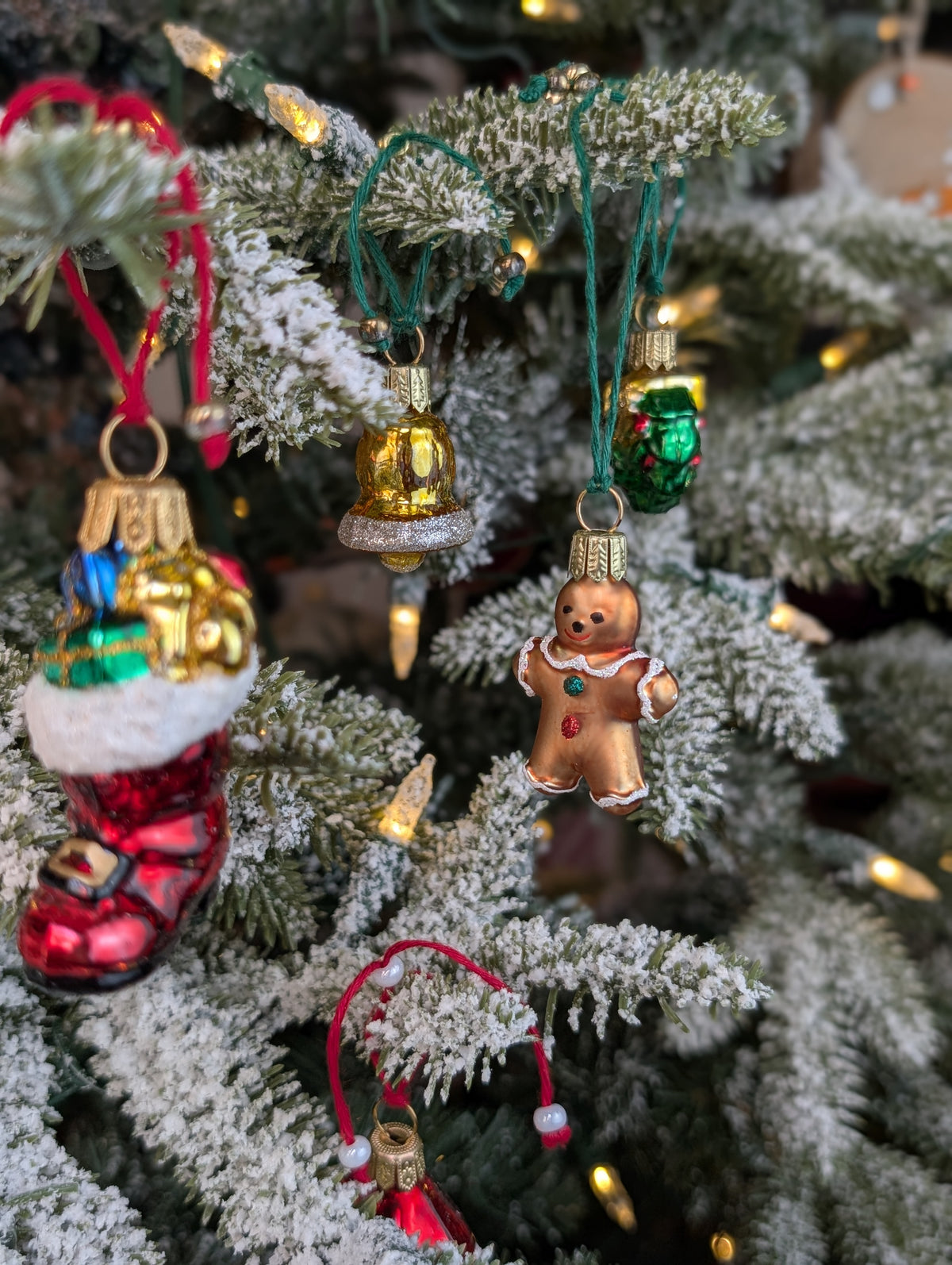Suspensions de Noël en verre soufflé, chromées et peintes à la main en forme de bonhomme en pain d'épices, de botte du père Noël remplie de cadeaux, de cloche dorée avec paillettes argentées et de couronne de noël verte.