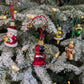 Suspensions de Noël en verre soufflé, chromées et peintes à la main en forme de voiture rouge avec des paquets cadeaux, de père noël tenant un cadeau, de bonhomme en pain d'épice, de cloche dorée et de couronne de noël verte.