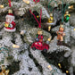 Suspensions de Noël en verre soufflé, chromées et peintes à la main en forme de voiture rouge avec des paquets cadeaux, de père noël tenant un cadeau, de bonhomme en pain d'épice, de cloche dorée, d'étoile dorée et de couronne de noël verte.