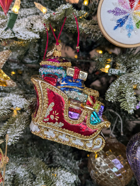 Suspension en forme de traineau du père Noël rouge et doré, garni de paquets cadeaux multicolores. 