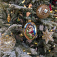 Suspensions de Noël représentant : un médaillon de forme ovale de la sainte famille : Marie, Joseph et Jésus enfant ; une boule en verre style ananas dorée ; un cœur transparent avec des dessins volutes blancs, argent et or ; une étoile en perles blanches et or 
