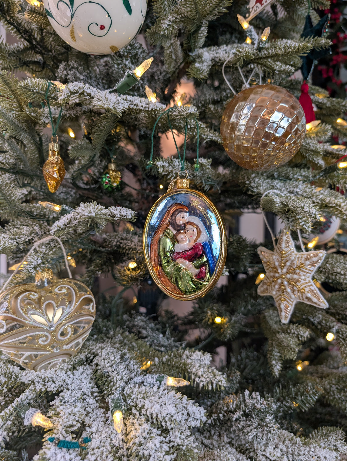 Suspensions de Noël représentant : un médaillon de forme ovale de la sainte famille : Marie, Joseph et Jésus enfant ; une boule en verre style ananas dorée ; un cœur transparent avec des dessins volutes blancs, argent et or ; une étoile en perles blanches et or 